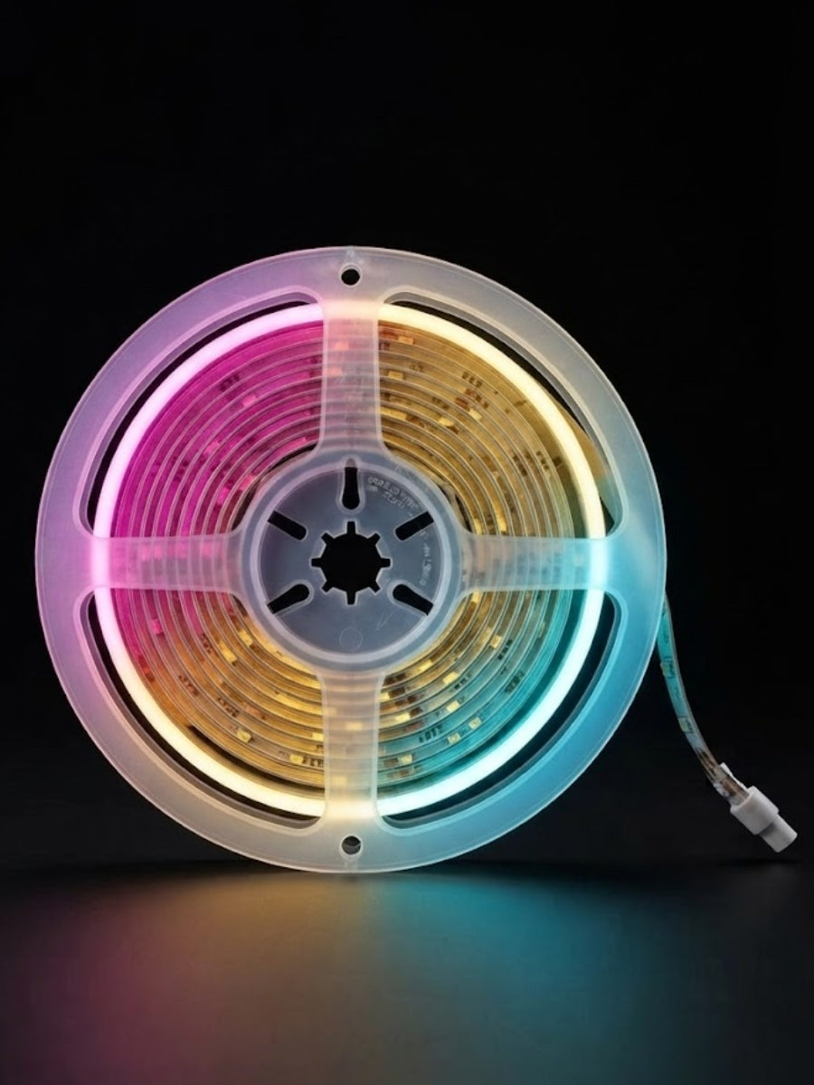 RGB LED strip light wound on a translucent reel and glowing pink, gold, and blue against black
