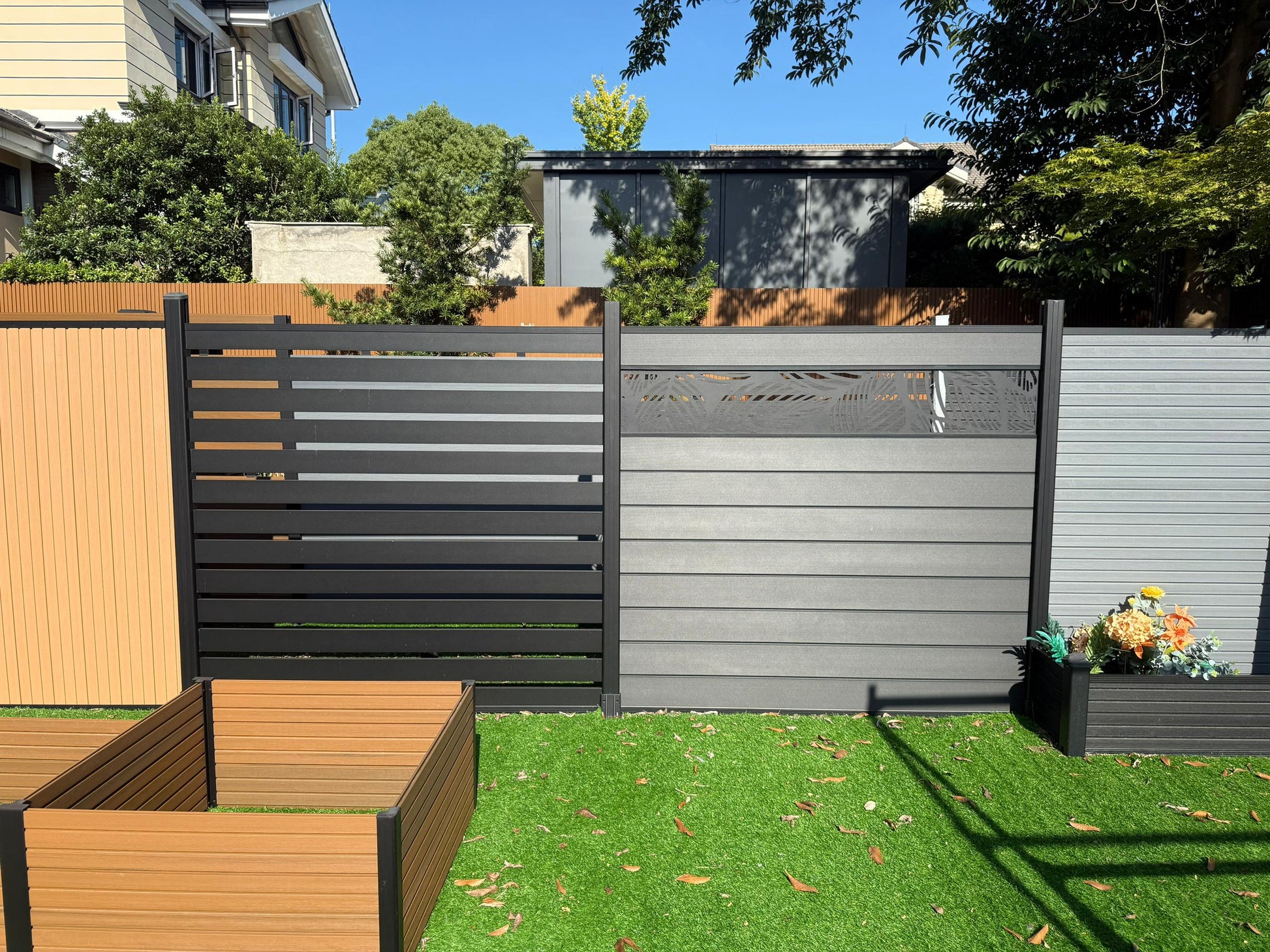 Garden scene with a wooden fence, gray privacy screen, and garden beds.