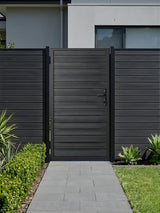 4x6 aluminum privacy gate installed in a matching dark fence along a modern garden walkway