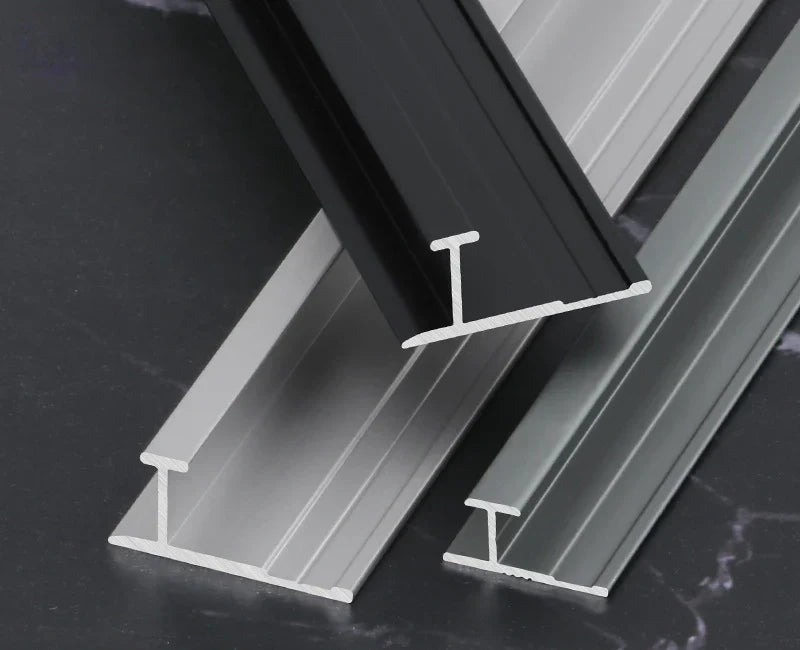 Black, silver, and gray I-shaped aluminum wall panel trim samples in multiple widths
