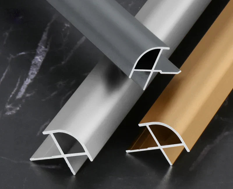 Silver, gray, and gold curved aluminum wall panel trim samples showing profile cross-sections