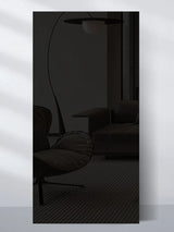 Dark glossy wall panel sample reflecting a modern lounge chair, sofa, and floor lamp