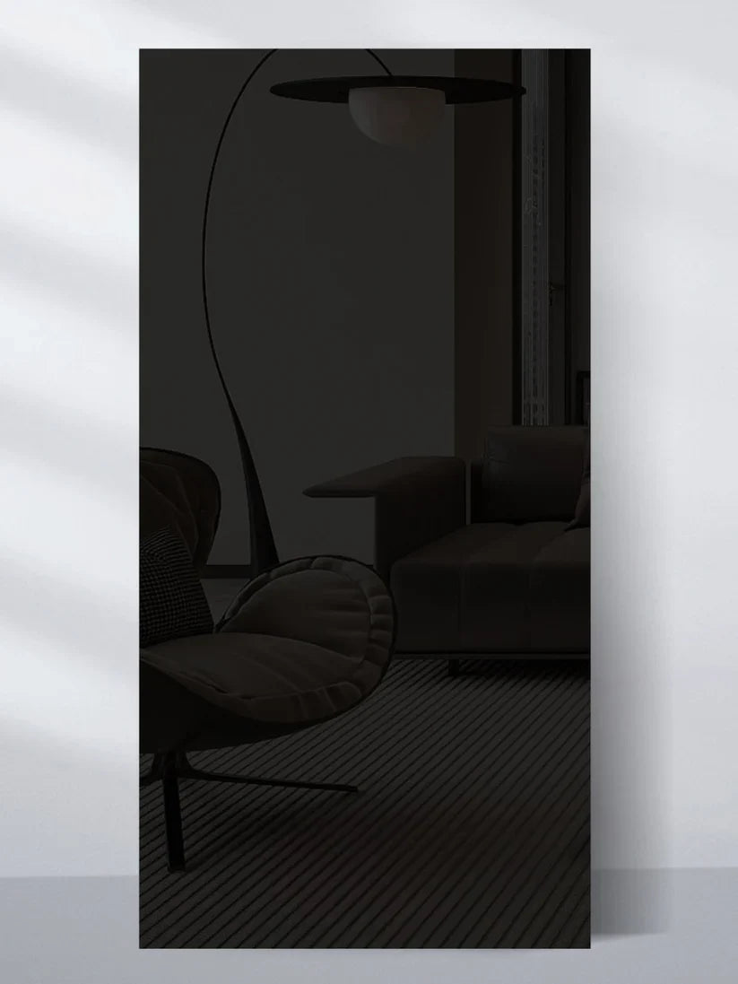 Dark glossy wall panel sample reflecting a modern lounge chair, sofa, and floor lamp