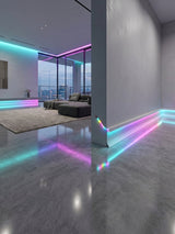 White aluminum LED baseboard molding casting cyan and magenta accent light in a modern living room