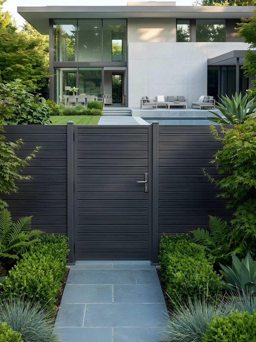 Dark aluminum full-privacy fence gate installed on a garden path leading to a modern home