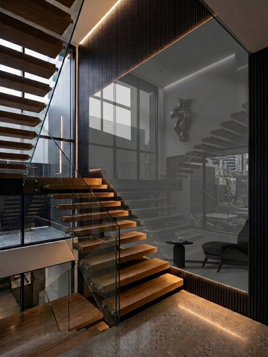 Gray mirror wood veneer panel installed beside a floating wood staircase in a modern double-height interior