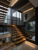 Black Mirror wood veneer panel installation reflecting a modern wood and glass staircase