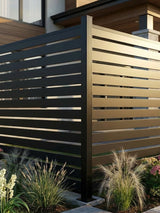 Corner installation of black aluminum open slat fence panels in a landscaped yard