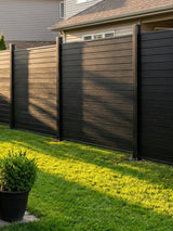 Black aluminum full privacy fence panels installed along a grassy residential backyard