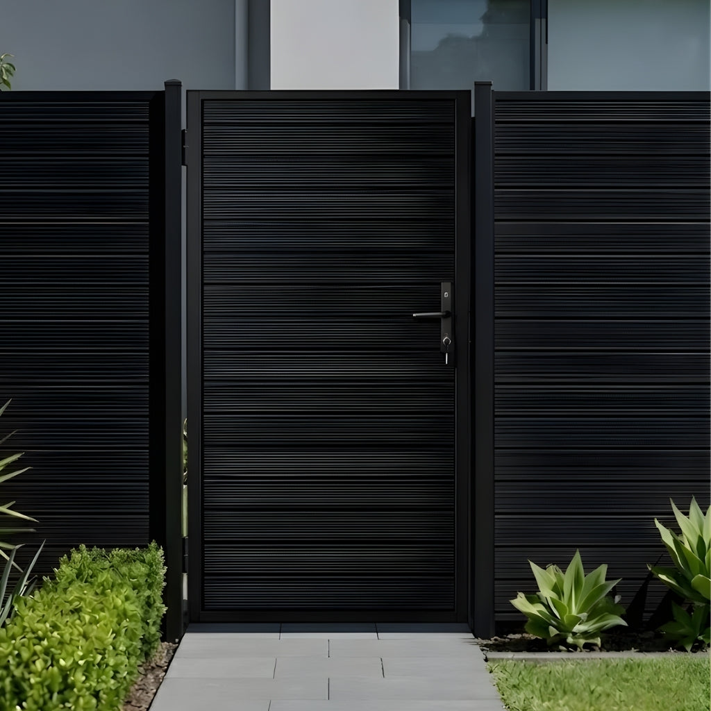 Dark aluminum privacy fence gate installed along a paved garden entry with matching fence panels