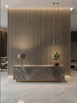 Illuminated Ash Wood WPC fluted 3D reception wall behind a stone desk