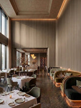 Commercial-grade ash wood veneer panels lining tall restaurant walls with warm lighting and upholstered booths