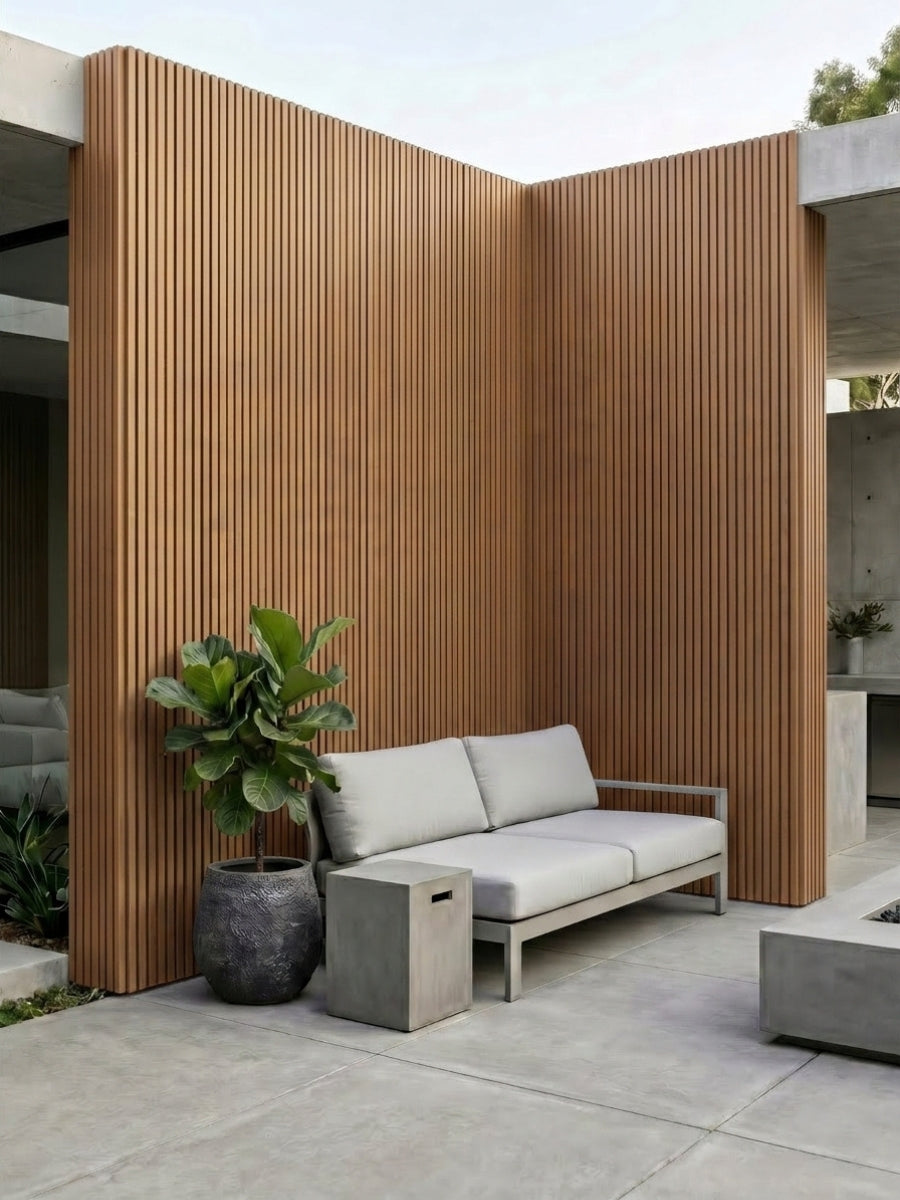Brown composite wide exterior cladding with black grooves covering courtyard walls behind an outdoor sofa