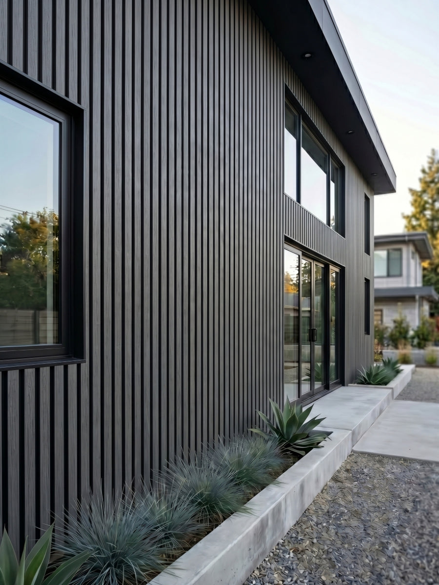 Gray and black composite cladding installed vertically on a modern two-story home exterior