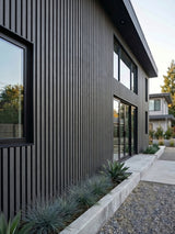 Gray and black composite cladding installed vertically on a modern two-story home exterior