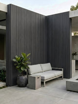 Wide gray and black composite cladding on tall courtyard walls beside outdoor seating