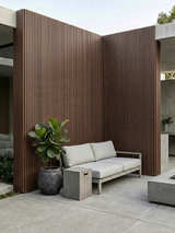 Brown composite wide exterior cladding installed on tall courtyard walls behind a sofa and planter