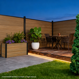 Walnut co-extruded composite fence enclosing an illuminated patio dining area
