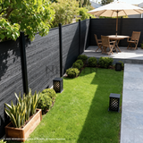 Black composite privacy fence installed around a landscaped garden dining area