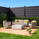 Black composite privacy fence behind wicker patio seating and a stone coffee table
