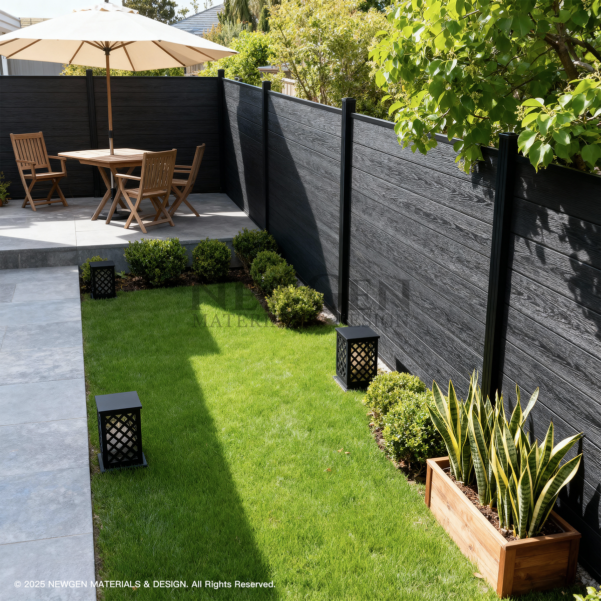 Black composite garden fence bordering a lawn with planters, lanterns, and outdoor dining furniture