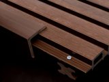 Close-up of dark brown composite cladding with L-shaped trim, mounting screw, clip, and grooved edge