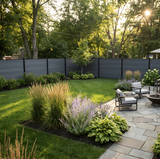 Light gray composite privacy fence enclosing a landscaped backyard lawn and stone patio