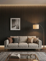 Dark Smoky Oak fluted wall panels behind a gray sofa with framed art and warm lighting