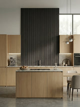 Dark Smoky Oak fluted 3D wall panel accent above the counter in a light wood kitchen