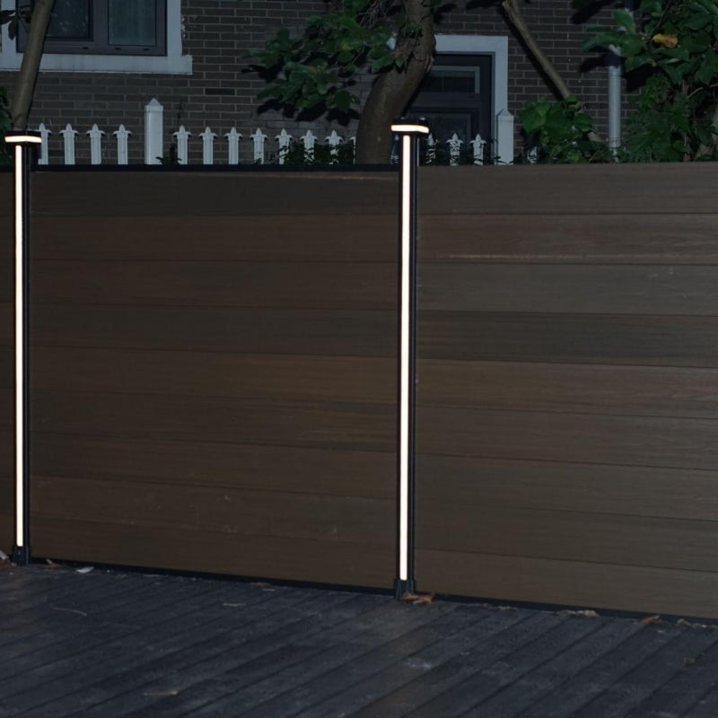 Two illuminated LED strips on posts along a dark composite privacy fence