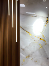 Three illuminated LED strip lights mounted between wood slats beside a marble-pattern wall