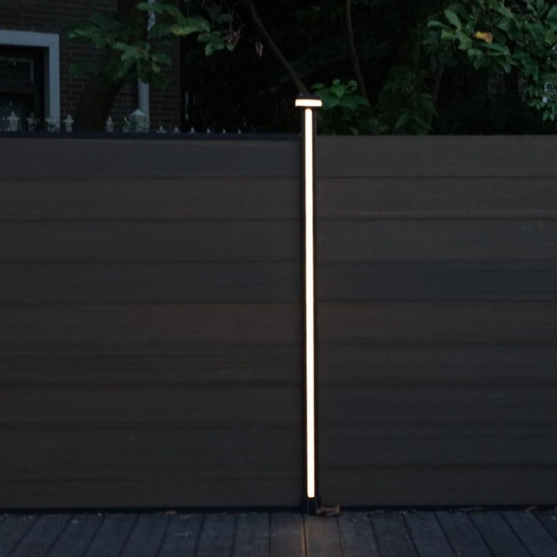 Vertical LED strip glowing on a composite garden fence post