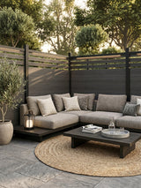 Black composite privacy fence with slatted lattice top surrounding an outdoor sofa area
