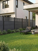 Black lattice-top composite privacy fence installed along a modern home's landscaped lawn