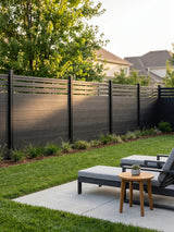 Black composite privacy fence with slatted lattice top enclosing a backyard patio and lawn