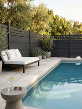 Black lattice-top composite privacy fence installed around a poolside seating area