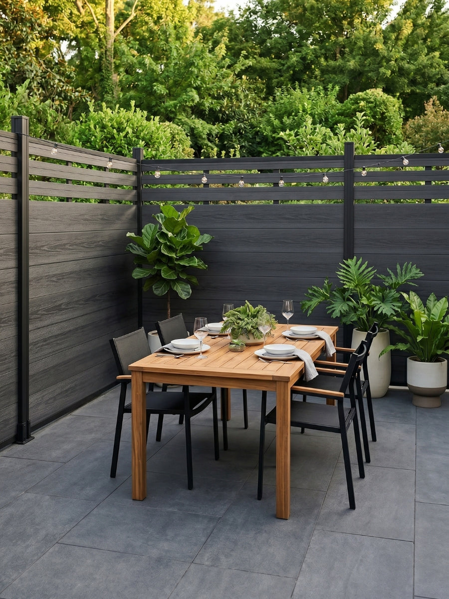 Black lattice-top composite privacy fence enclosing an outdoor dining patio with plants