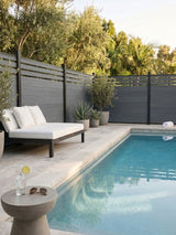 Light gray composite privacy fence surrounding a poolside patio with lounge seating