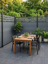 Light gray composite privacy fence enclosing a patio dining area with plants