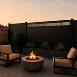 Modern decorative fence screen with vertical slats topping a dark patio fence behind lounge chairs and a fire pit