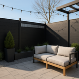 Modern decorative fence screen with vertical slats on a dark patio fence behind an outdoor sofa and string lights