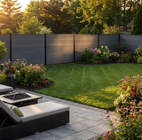 Light gray composite privacy fence behind a landscaped lawn and outdoor lounge area
