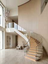 Curved staircase set against a double-height wall clad in Nordic birch wood veneer panels