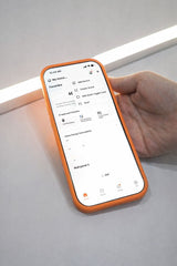 Smartphone displaying app controls beside an illuminated LED strip light