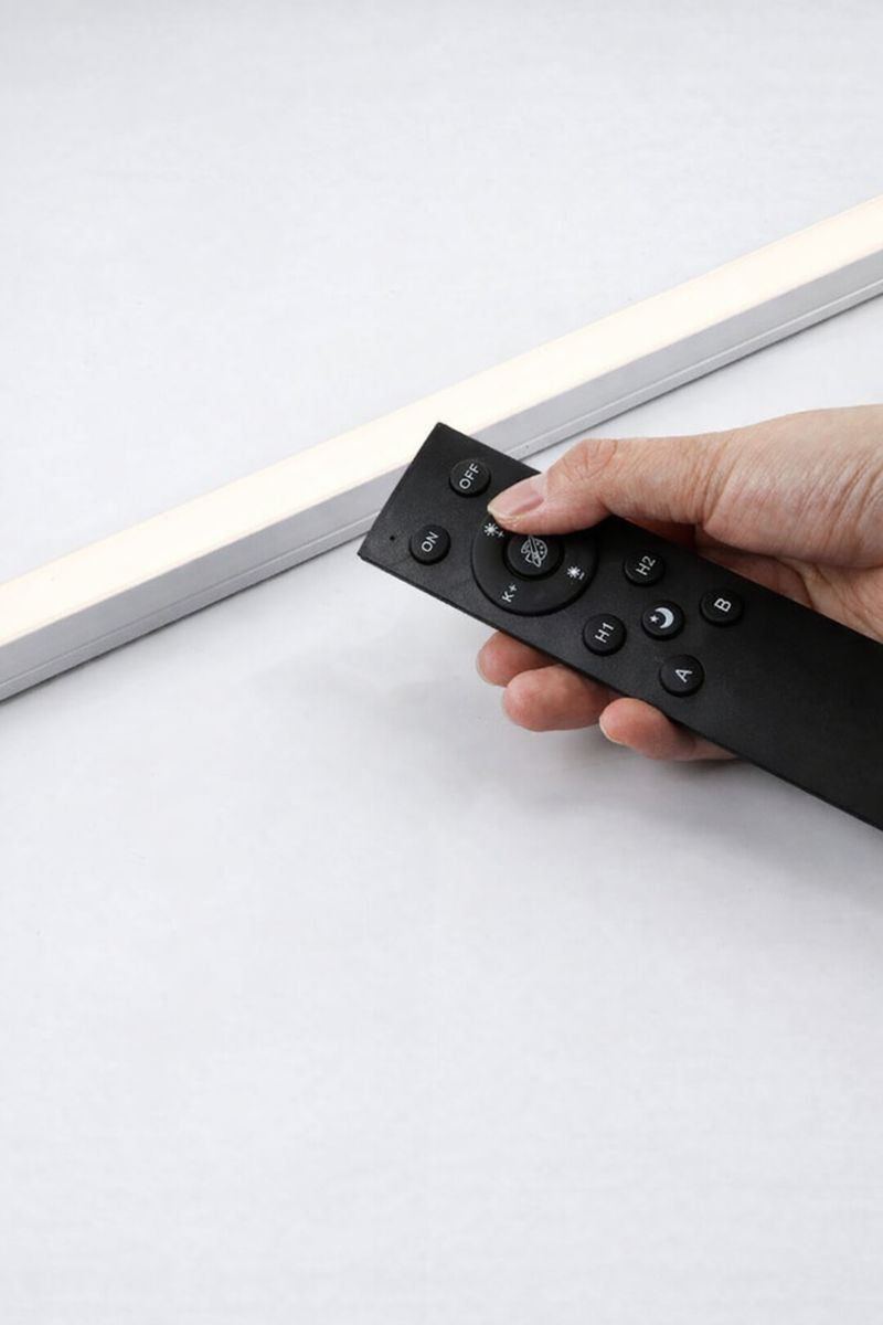Hand using the black remote beside an illuminated smart LED strip light