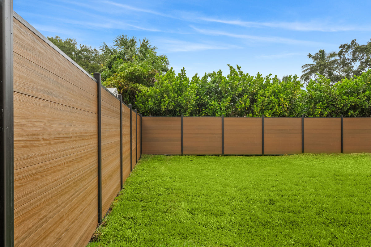 Walnut composite privacy fence with black posts enclosing a green lawn