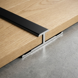 Black aluminum alloy H trim installed between two wood-look wall panels on a gray surface