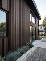 Modern house facade finished with dark brown and black composite vertical exterior cladding