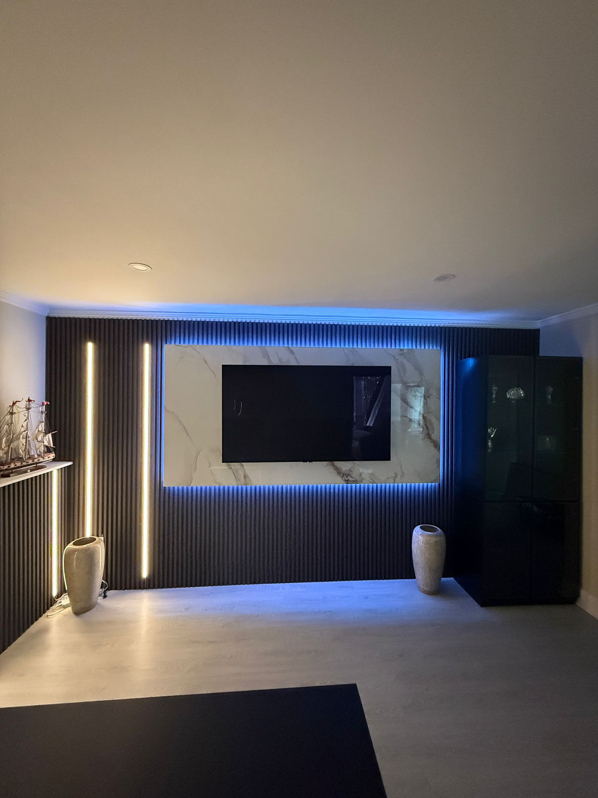 Smart LED strip lights casting blue and warm white accent lighting around a wall-mounted TV