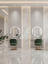 White brushed fluted wall panels framing round illuminated mirrors and green chairs in a salon